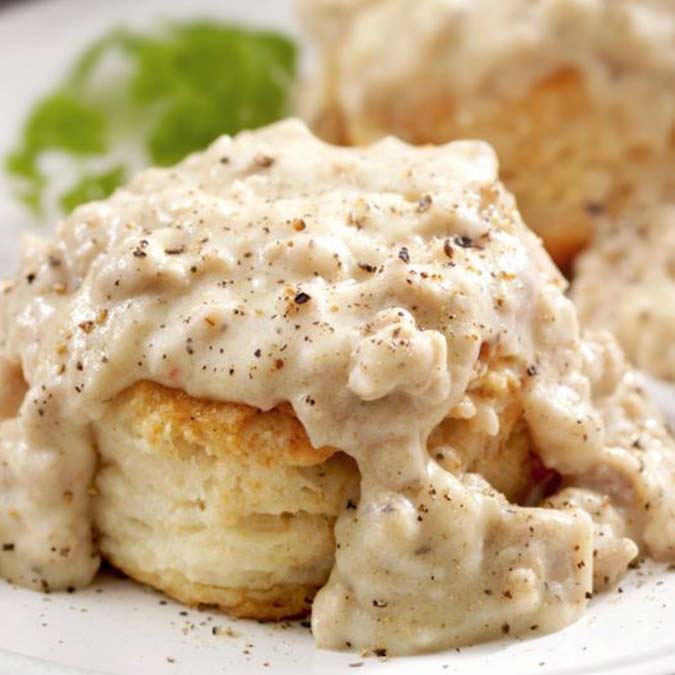 A flaky biscuit with creamy sausage gravy at E.J.'s Diner Wausau, topped with black pepper.