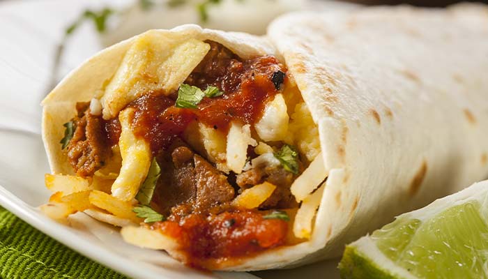 A close-up of a breakfast burrito in Wausau, WI, filled with beef, cheese, and salsa.