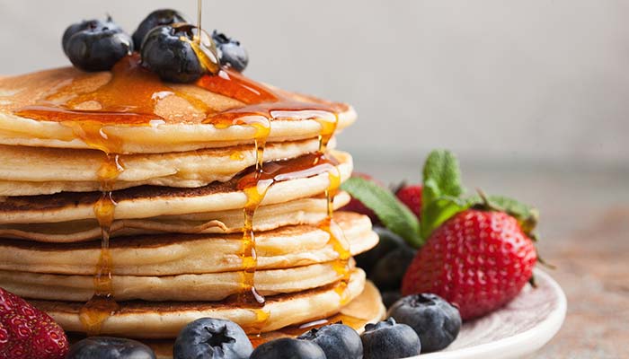 A stack of pancakes with syrup and berries, perfect for breakfast in Wausau, WI.