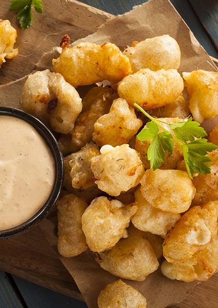 Golden fried cheese curds from E.J.'s Diner Wausau, served with sauce and parsley on top.