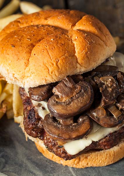 Close-up of E.J.'s Diner Wausau mushroom Swiss burger with fries on the side.
