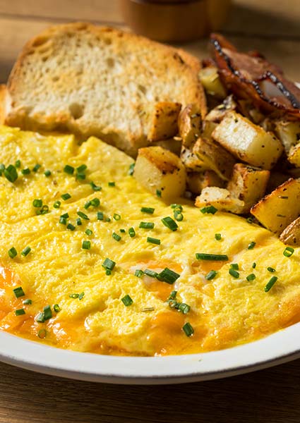 Omelette with chives, toast, and potatoes served at E.J.'s Diner Wausau on a white plate.
