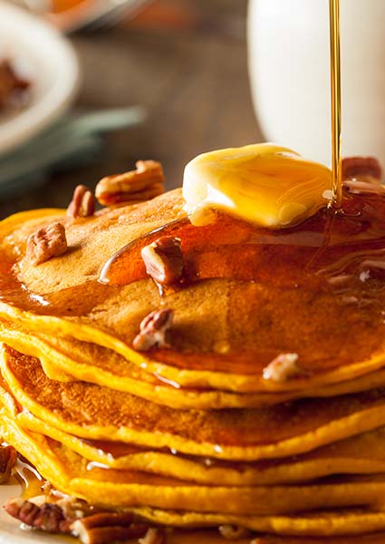 Stack of pancakes from E.J.'s Diner Wausau, topped with butter, syrup, and pecans.