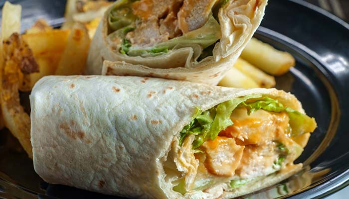 Chicken wrap with lettuce and sauce, served with fries—a tasty lunch in Wausau, WI.